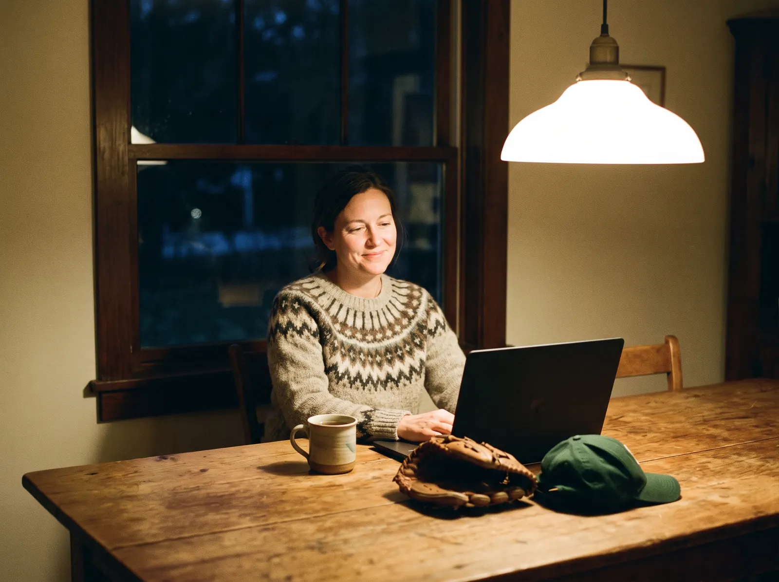 A volunteer board member smiling at her laptop at the kitchen table in the evening